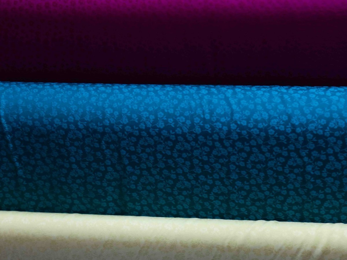 Rolls of coloured fabric stacked in a textile warehouse